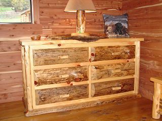A wooden dresser is sitting in a wooden room next to a lamp.