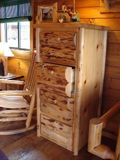 A wooden dresser and rocking chair in a log cabin.