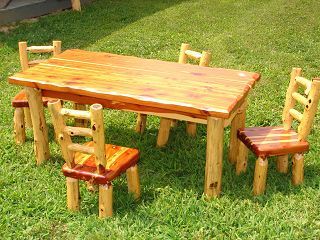 A wooden table and chairs are sitting in the grass.