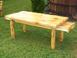 A wooden table with a drawer underneath it is sitting on top of a lush green field.
