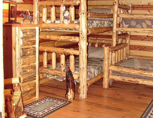 A room with bunk beds made of logs and a rug