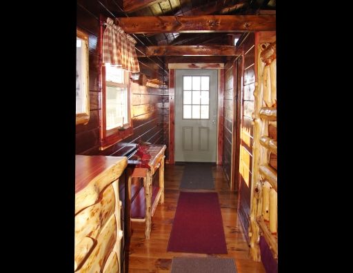 A hallway in a log cabin with a red rug