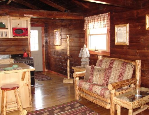 A living room in a log cabin with a couch and chairs
