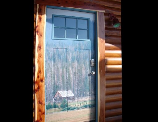 A blue door with a painting of a cabin in the woods on it.