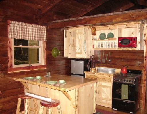 A kitchen in a log cabin with a stove and a refrigerator