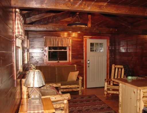 A living room in a log cabin with a couch and chairs