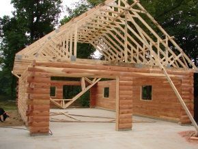 A log cabin is being built with a wooden roof.