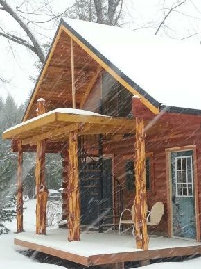 A log cabin with a porch and chairs in the snow