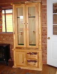 A wooden cabinet with glass doors and drawers is sitting in a room next to a door.