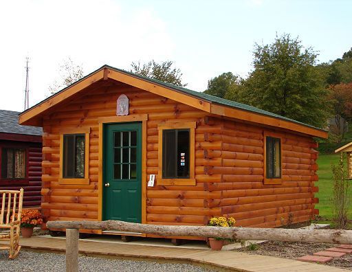 A small log cabin with a green door and windows