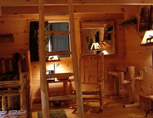 A wooden room with a ladder leading up to the second floor