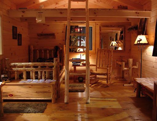 A wooden room with a bed and chairs and a ladder