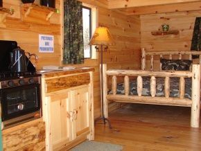 A wooden cabin with a bed and a stove