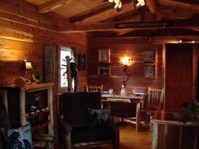A living room in a log cabin with a table and chairs