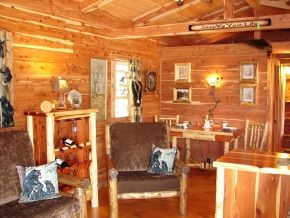 A living room in a log cabin with a couch and chairs