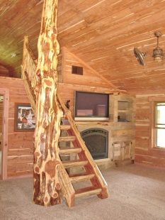 A log cabin with a staircase made out of a tree trunk and a fireplace.