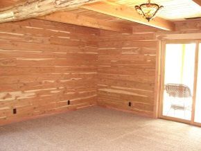 An empty room with wooden walls and a sliding glass door.