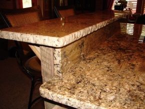 A granite counter top in a kitchen with a wooden table and chairs.