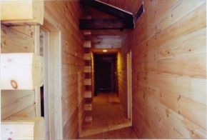 A wooden hallway with a staircase going up to the second floor