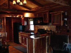 A kitchen in a log cabin with a black refrigerator