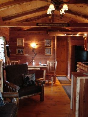 A living room in a log cabin with a table and chairs