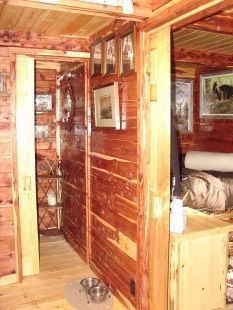 A hallway in a log cabin with two bowls on the floor.
