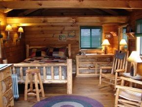 A wooden cabin with a bed , chairs , lamps and a rug.