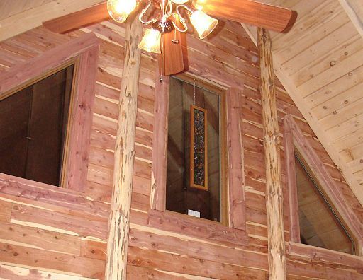 A ceiling fan is hanging from the ceiling of a log cabin
