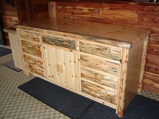 A wooden cabinet with drawers and doors is sitting in front of a wooden wall.