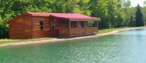 A log cabin is sitting on the shore of a lake.
