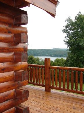 A log cabin with a wooden deck overlooking a lake