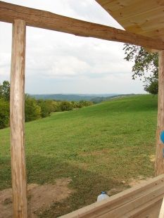 A view of a grassy hill from a wooden porch