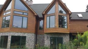 A large wooden and stone house with a lot of windows.
