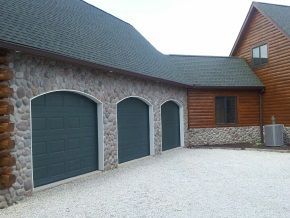 There are three garage doors on the side of a house.