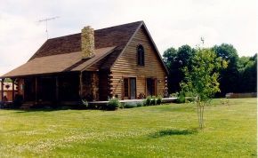 A log cabin is sitting in the middle of a lush green field.