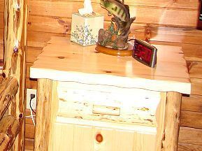 A wooden nightstand with a lamp and a clock on it.