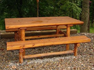 A wooden picnic table and bench are sitting on a gravel area.