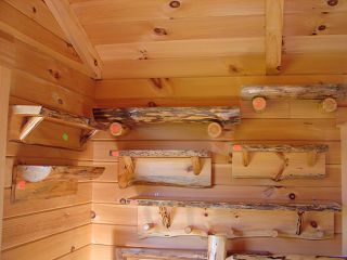 A wooden wall with wooden shelves and hooks on it.
