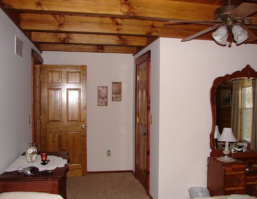A bedroom with a ceiling fan and a mirror