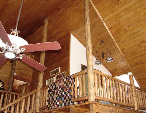 A ceiling fan is hanging from the ceiling of a log cabin