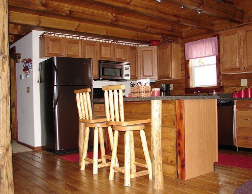 A kitchen in a log cabin with stools and a refrigerator