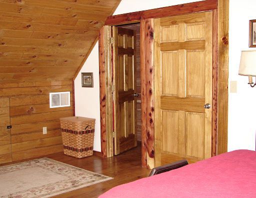 A bedroom with wood paneling and a red bed