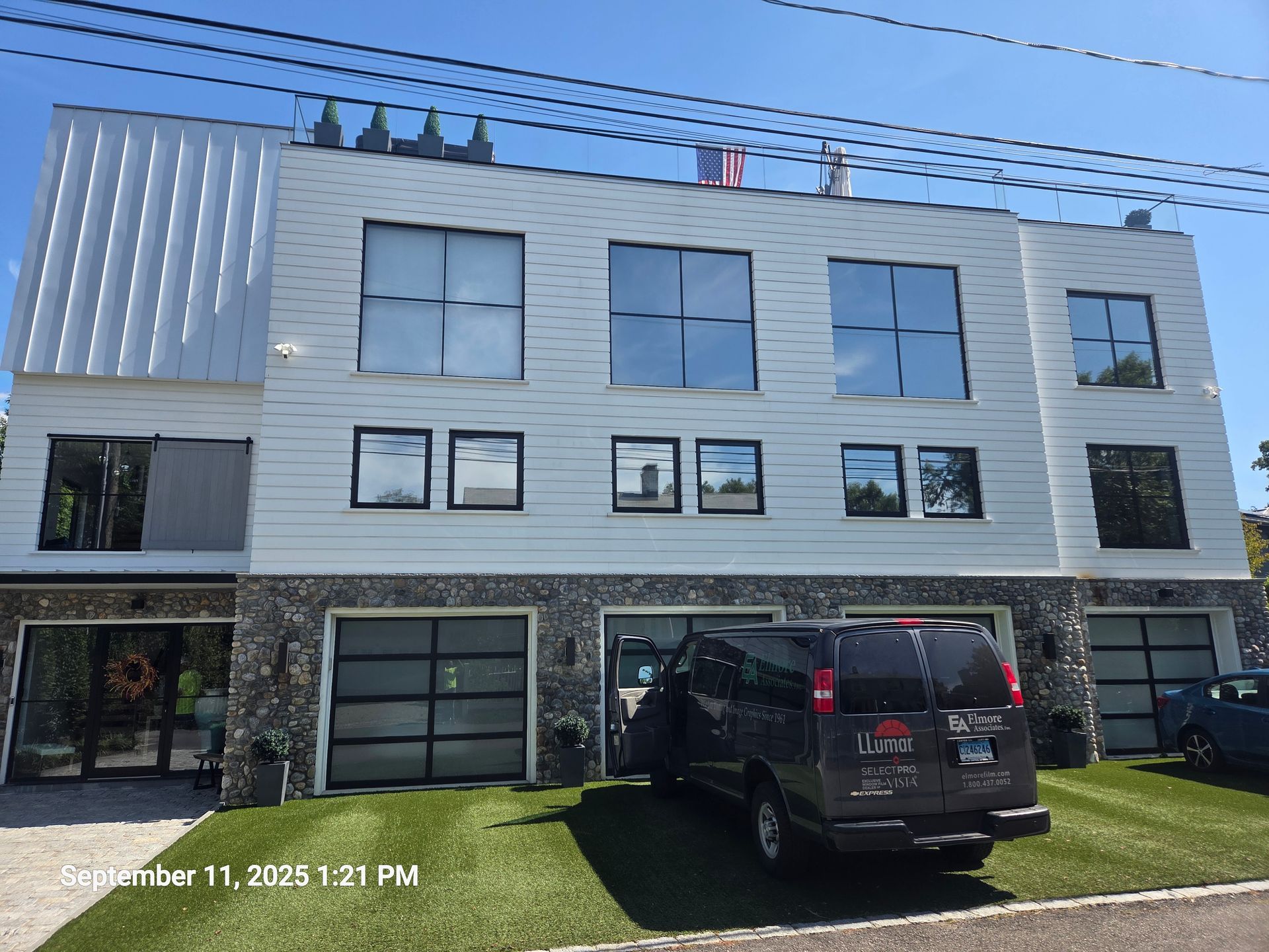 Modern three-story apartment building with gray siding, garage doors, and a black SUV parked in front
