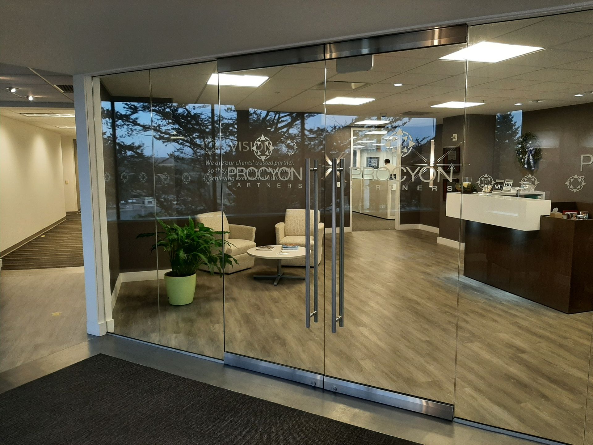 Modern office lobby with glass doors, lounge seating, and a reception desk.