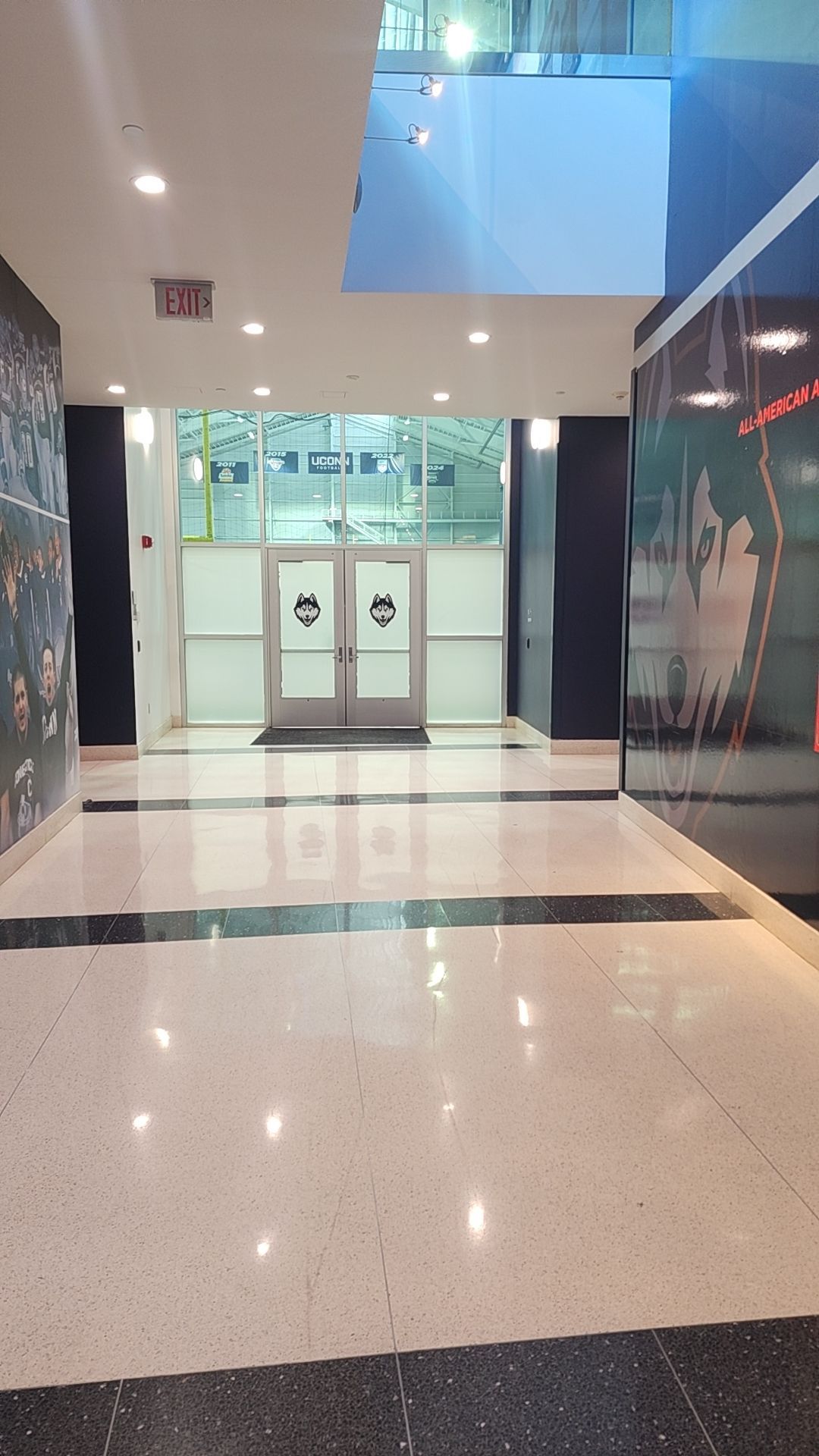 Empty shopping mall corridor with glossy floors, glass doors, and storefronts on both sides