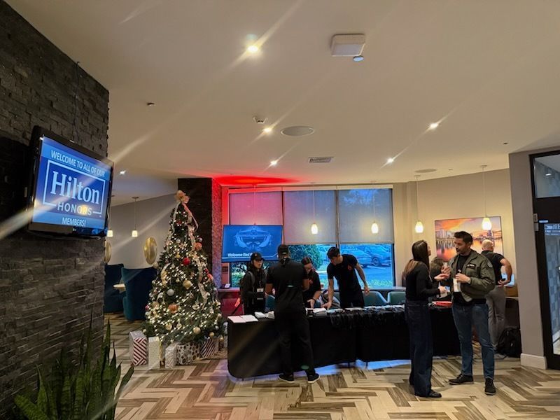 Hotel lobby holiday event with Christmas tree, registration table, and people mingling