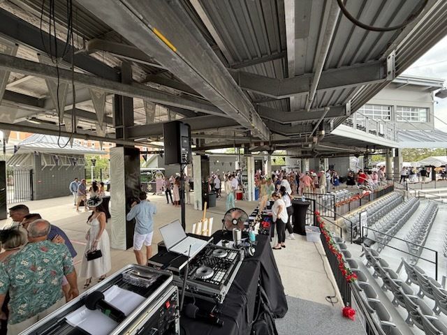 Racing grandstand with people walking past rows of metal bleachers and event equipment under a covered roof