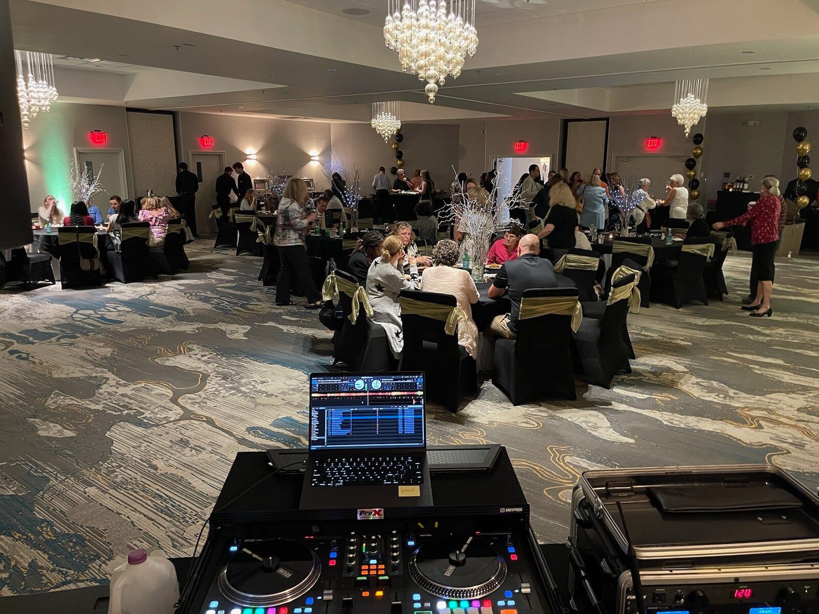 Banquet hall with seated guests and a DJ booth in the foreground