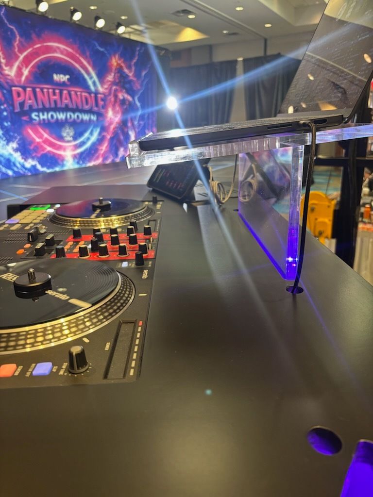 DJ booth in a conference hall with a large screen reading “PANHANDLE SHOWDOWN” and colorful stage lighting