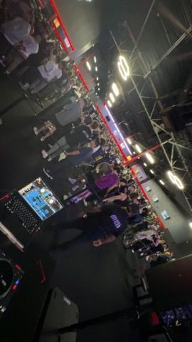 Crowded nightclub dance floor with people standing under neon lights and ceiling fixtures